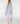 A woman modeling a light blue and white vertically striped long-sleeve nightshirt or tunic with a buttoned neckline, standing against a plain light gray studio background.